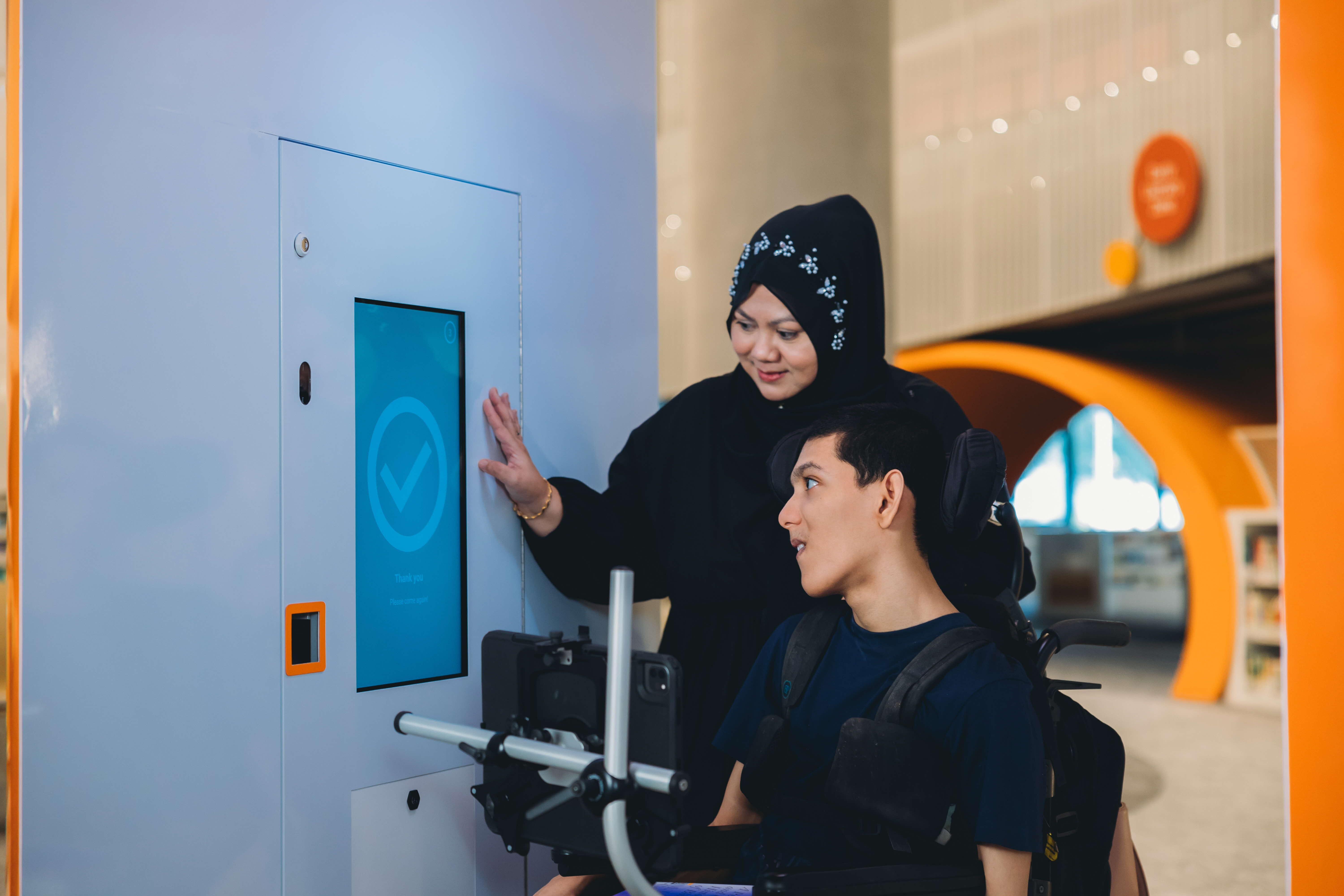 Photo of someone in a wheelchair using a touchscreen in a library
